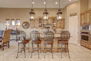 Kitchen with light tile patterned floors, appliances with stainless steel finishes, hanging light fixtures, and a kitchen island