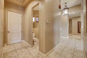 Hallway featuring an inviting chandelier and light tile patterned floors