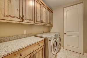 Laundry room with separate washer and dryer, cabinets, and light tile patterned flooring