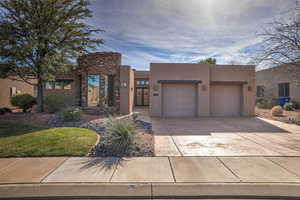 Pueblo revival-style home featuring a garage