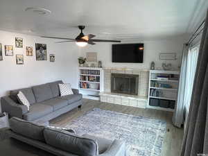 Living room with ceiling fan, a textured ceiling, and wood-type flooring