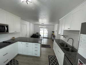 Kitchen with stainless steel appliances, white cabinetry, kitchen peninsula, and dark wood-type flooring