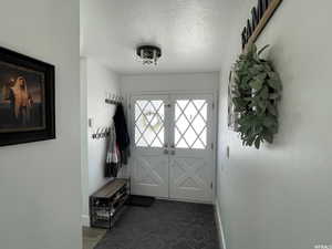 Doorway featuring french doors, a textured ceiling, and dark colored carpet