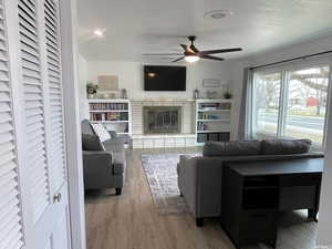 Living room featuring ceiling fan, a textured ceiling, and hardwood / wood-style flooring