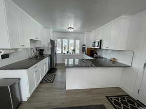 Kitchen with sink, stainless steel appliances, kitchen peninsula, and white cabinetry