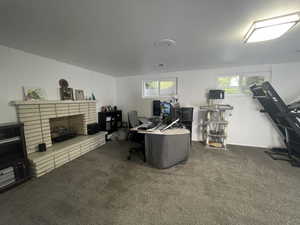 Home office with dark carpet, plenty of natural light, and a fireplace