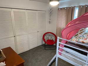 Bedroom with dark carpet and a closet