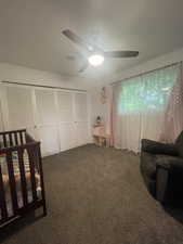 Bedroom featuring dark carpet, ceiling fan, and a closet