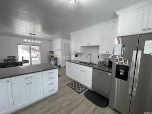 Kitchen featuring appliances with stainless steel finishes, light wood-type flooring, and white cabinetry