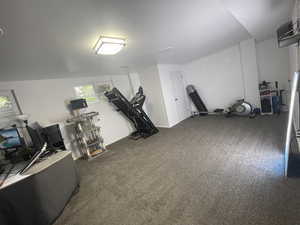 Workout room with dark colored carpet and lofted ceiling