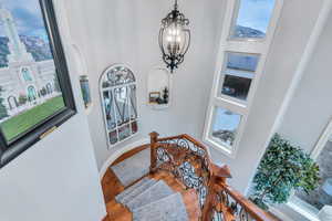 Staircase with an inviting chandelier, a wealth of natural light, and wood-type flooring