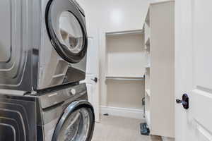 Laundry area with stacked washer / drying machine and light carpet