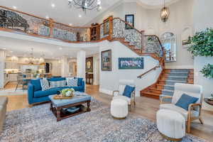 Living room featuring ornamental molding, a high ceiling, a chandelier, and light wood-type flooring