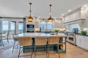 Kitchen with a center island, hanging light fixtures, light hardwood / wood-style flooring, decorative backsplash, and appliances with stainless steel finishes