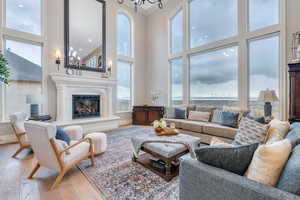 Living room with a high ceiling, ornamental molding, an inviting chandelier, and hardwood / wood-style flooring