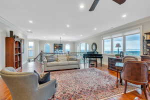 Living room featuring ceiling fan, light wood-type flooring, and ornamental molding