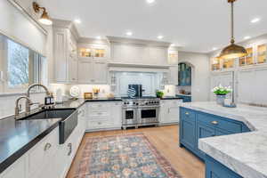 Kitchen with white cabinets, hanging light fixtures, blue cabinetry, and double oven range