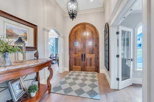 Entrance foyer featuring a healthy amount of sunlight, ornamental molding, an inviting chandelier, and light hardwood / wood-style flooring