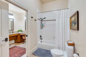 Full bathroom with shower / tub combo with curtain, vanity, toilet, and tile patterned floors