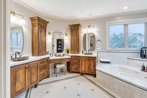 Bathroom with vanity, tile patterned floors, tiled bath, crown molding, and ornate columns