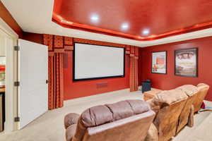 Home theater featuring light carpet and a tray ceiling