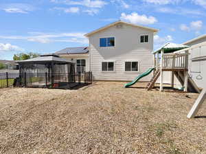 Back of property featuring a playground and a gazebo