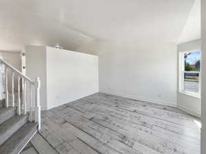 Empty room featuring light wood-type flooring and vaulted ceiling