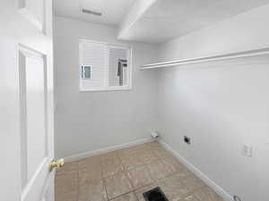 Laundry area featuring light tile patterned floors and electric dryer hookup