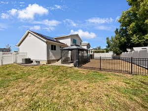 Back of house featuring solar panels, a gazebo, a yard, and central air condition unit