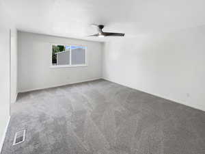 Carpeted empty room featuring ceiling fan