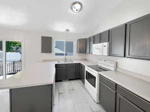 Kitchen with light hardwood / wood-style flooring, white appliances, vaulted ceiling, and sink