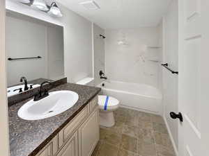 Full bathroom featuring a textured ceiling, shower / bathtub combination, tile patterned floors, vanity, and toilet