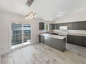 Kitchen featuring light hardwood / wood-style floors, vaulted ceiling, white appliances, pendant lighting, and sink