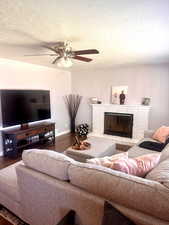 Living room featuring ceiling fan, a textured ceiling, and dark hardwood / wood-style flooring