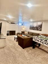 Living room featuring a brick fireplace, a textured ceiling, and carpet