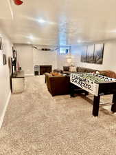 Rec room with carpet flooring, a textured ceiling, and a fireplace