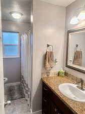 Bathroom featuring tile patterned flooring, a textured ceiling, a shower with shower curtain, vanity, and toilet