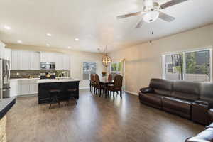 Living room with wood-type flooring, a textured ceiling, ceiling fan with notable chandelier, and sink