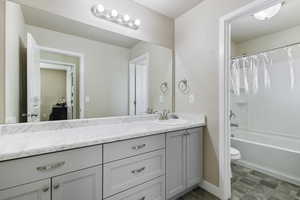 Full bathroom with shower / bath combination with curtain, vanity, and toilet