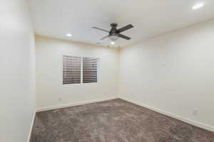 Spare room featuring dark carpet and ceiling fan