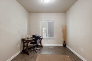 Office space with dark hardwood / wood-style floors