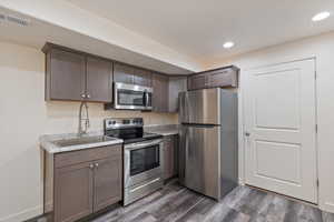 Kitchen with dark brown cabinets, appliances with stainless steel finishes, dark hardwood / wood-style floors, and sink