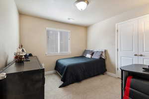 Bedroom with light carpet, a textured ceiling, and a closet