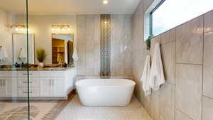 Bathroom featuring tile walls, tile patterned flooring, a bath, and vanity