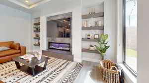 Living room featuring built in shelves, a tiled fireplace, and hardwood / wood-style floors