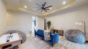 Bedroom featuring a tray ceiling, light hardwood / wood-style floors, and ceiling fan