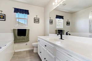 Bathroom with a bathing tub, vanity, toilet, and tile patterned floors