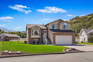 View of front facade with a garage, a front lawn, and central AC