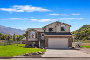 View of front of property with a garage, a mountain view, and a front lawn