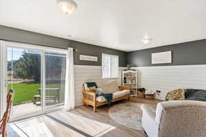 Living room with light hardwood / wood-style floors, wooden walls, and plenty of natural light